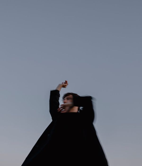 Person doing an energetic yoga warrior pose against a dark background.